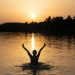 a person in a body of water with their arms in the air