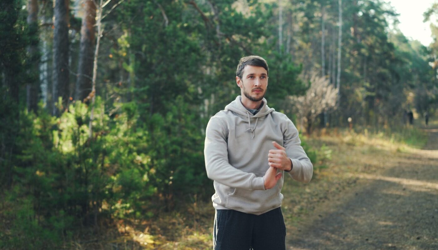 Man stretching outdoors in a forest setting.