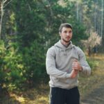 Man stretching outdoors in a forest setting.