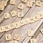 scrabble tiles spelling the word mindfulness on a wooden surface