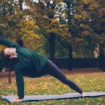 Woman practicing yoga on mat in autumn park